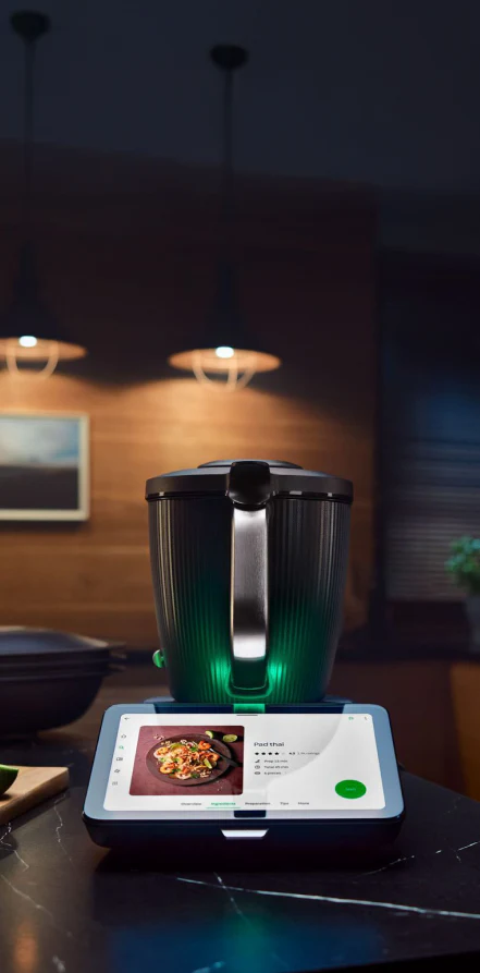 Smart kitchen appliance on a counter with a tablet displaying a recipe.